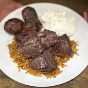plate of cooked afelia pork with pourgouri and greek yogurt