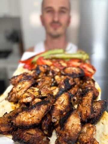 niko holding plate of greek chicken wings ready for eating