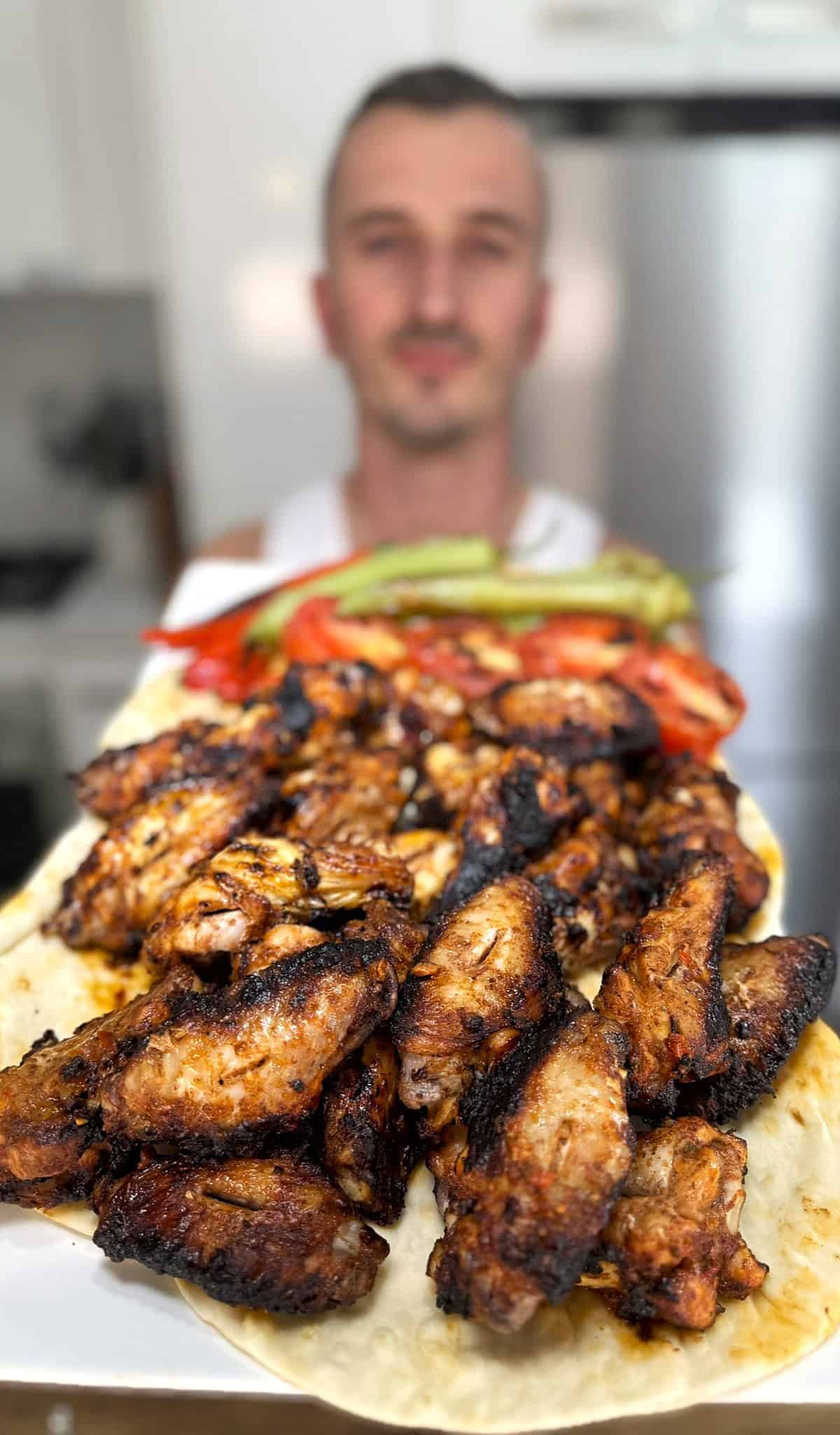 niko holding plate of greek chicken wings ready for eating