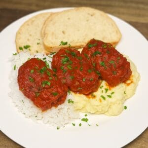 greek soutzoukakia on a plate in tomato sauce ready to be eaten
