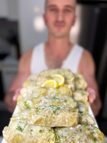 niko holding a plate with cooked lahanodolmades ready for eating