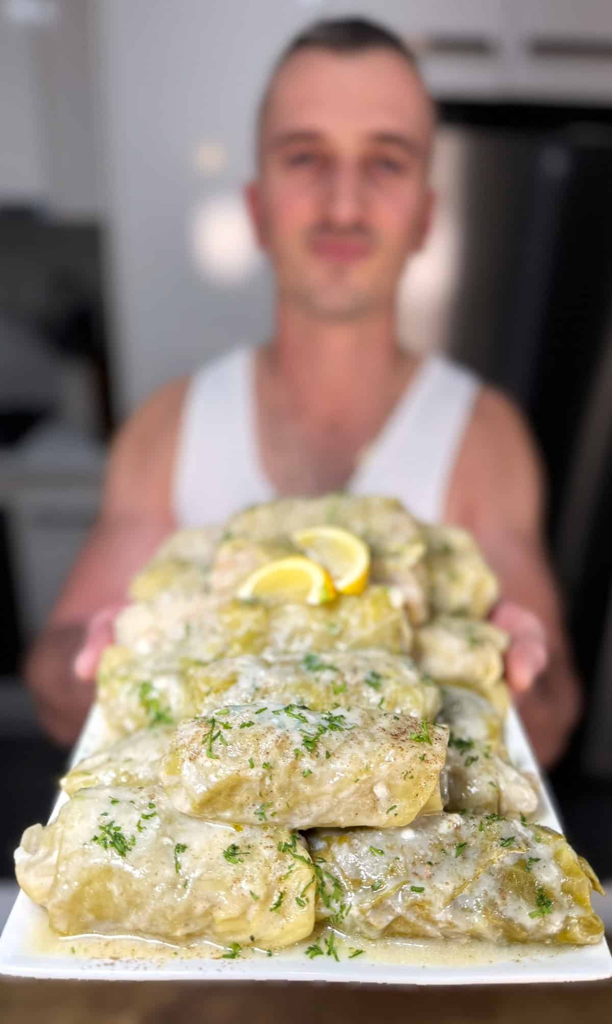 niko holding a plate with cooked lahanodolmades ready for eating