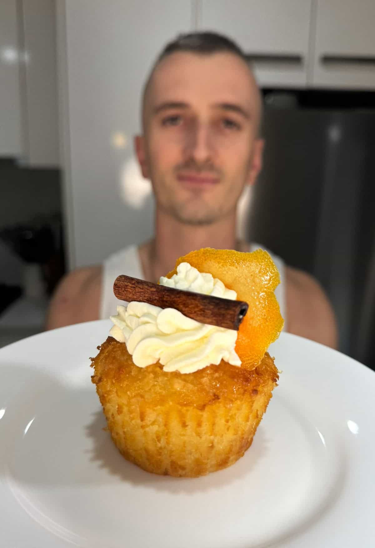 niko holding a greek orange cupcake garnished with cream, orange and cinnamon