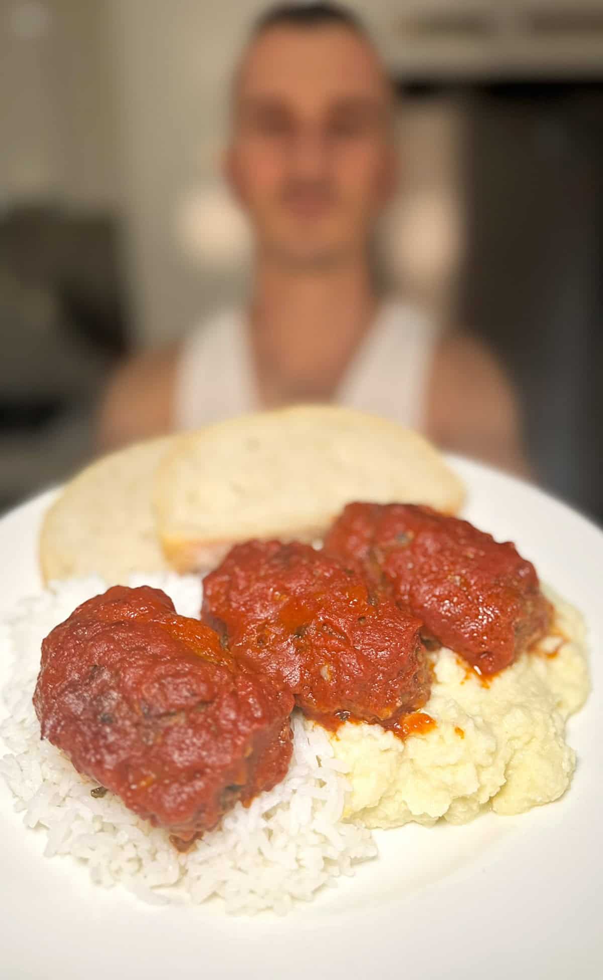 niko holding a plate of soutzoukakia in tomato sauce